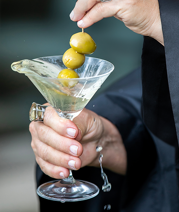 Close-up of a martini glass with olives and a splash of vodka, made with premium plant-based I’m parched! vodka from Texas